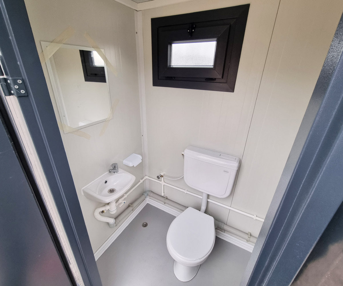 Contenedor sanitario nuevo de formato compacto, equipado con WC, urinario y lavabo.