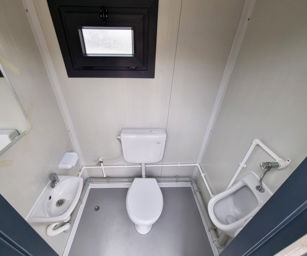Contenedor sanitario nuevo de formato compacto, equipado con WC, urinario y lavabo.