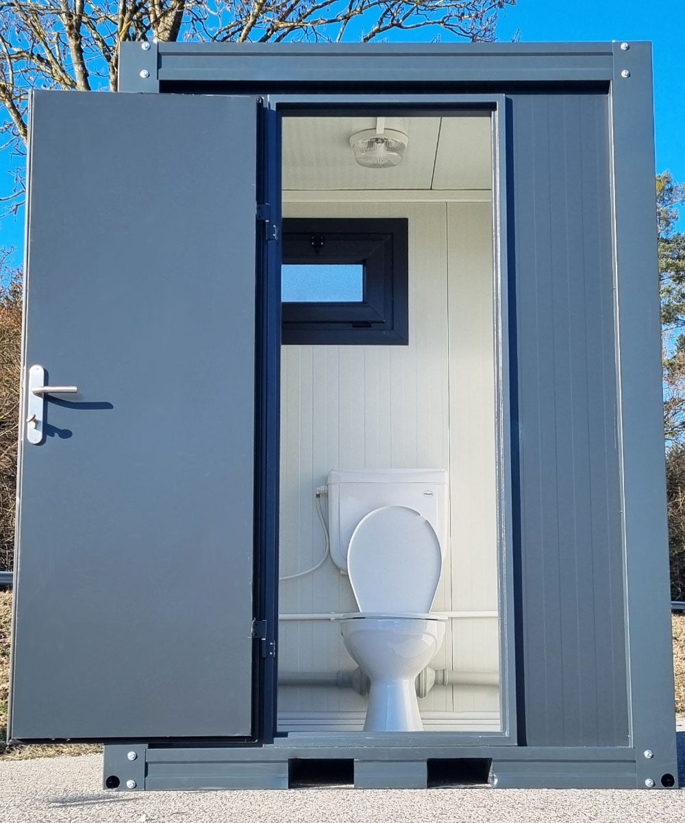 Contenedor sanitario nuevo de formato compacto, equipado con WC, urinario y lavabo.